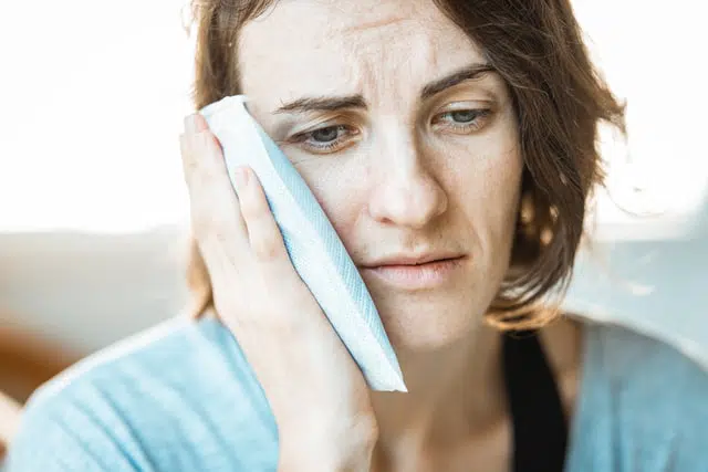 woman with an ice pack on her cheek
