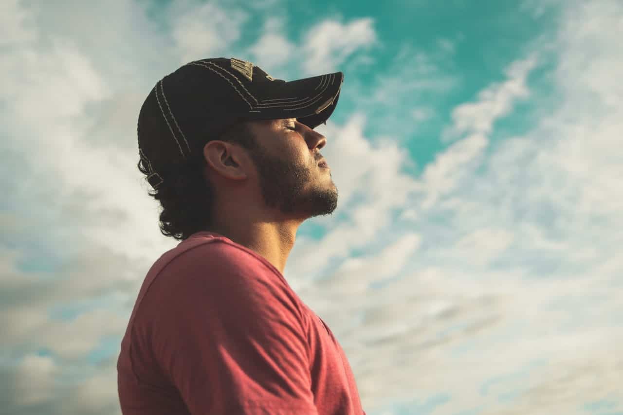 man with his closed eyes with a sky background