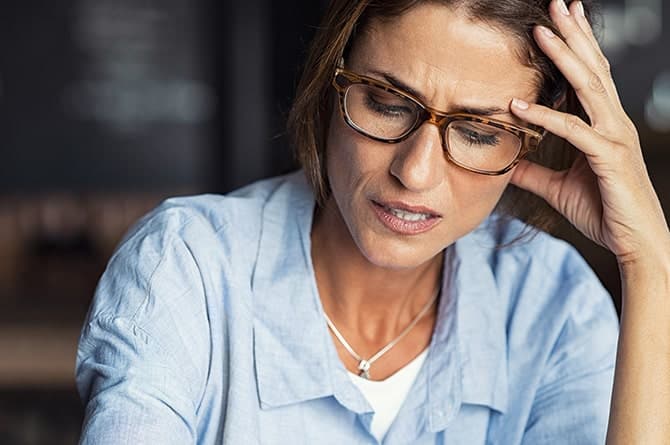 Stressed woman with glasses suffering from migraine 