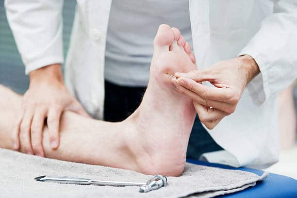 Doctor examining a diabetic patient's foot by poking it with something sharp.