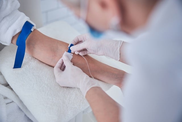 cropped image of a medical specialist administering ketamine infusion on a patients arm