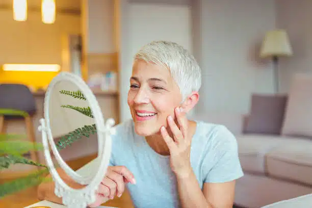 Middle aged woman is looking herself at the mirror after getting a vitamin c iv therapy