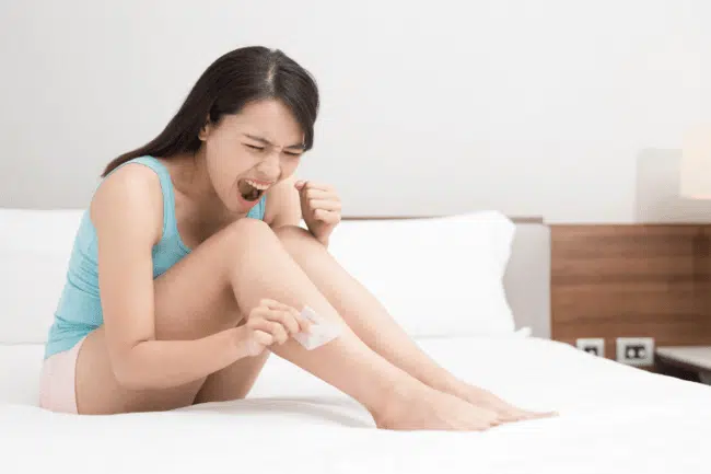 Young girl waxing her leg to remove the hair on her legs.