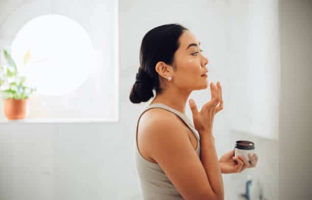 woman applying some topical exosome products to her face at home 