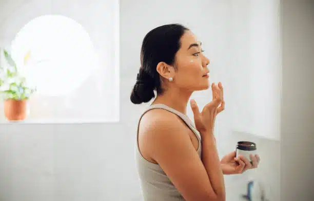 woman applying some topical exosome products to her face at home 