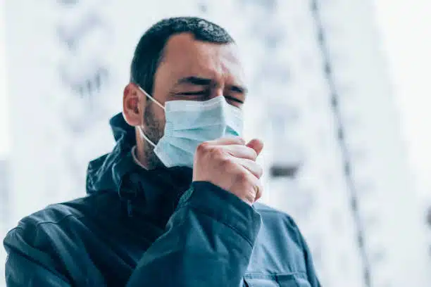 Man wearing a mask suffers from flu and cough due to poor immune system.