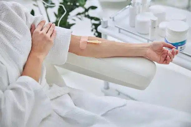 Female patient sitting in medicine armchair while receiving IV infusion in wellness center.