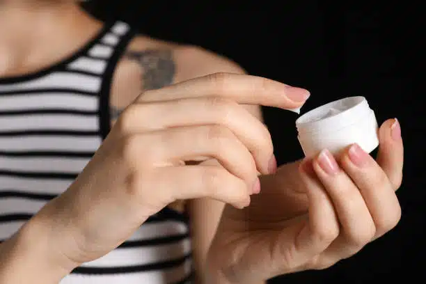 Woman holding a Tattoo Removal Cream in her hand.
