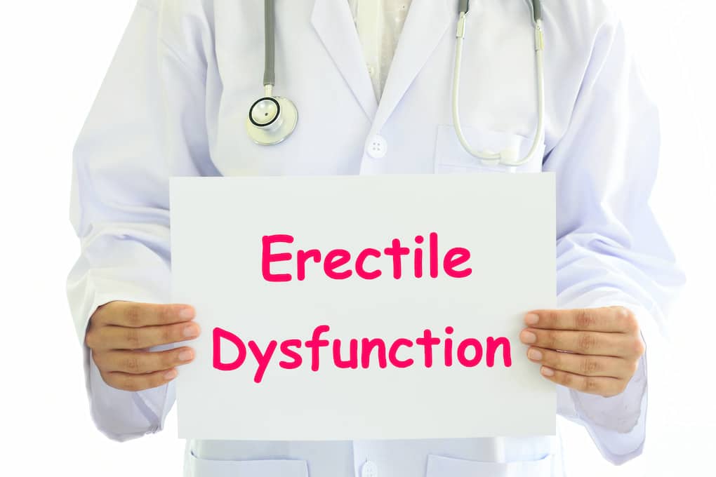 Doctor holding a white card board with Erectile Dysfunction concept on it.