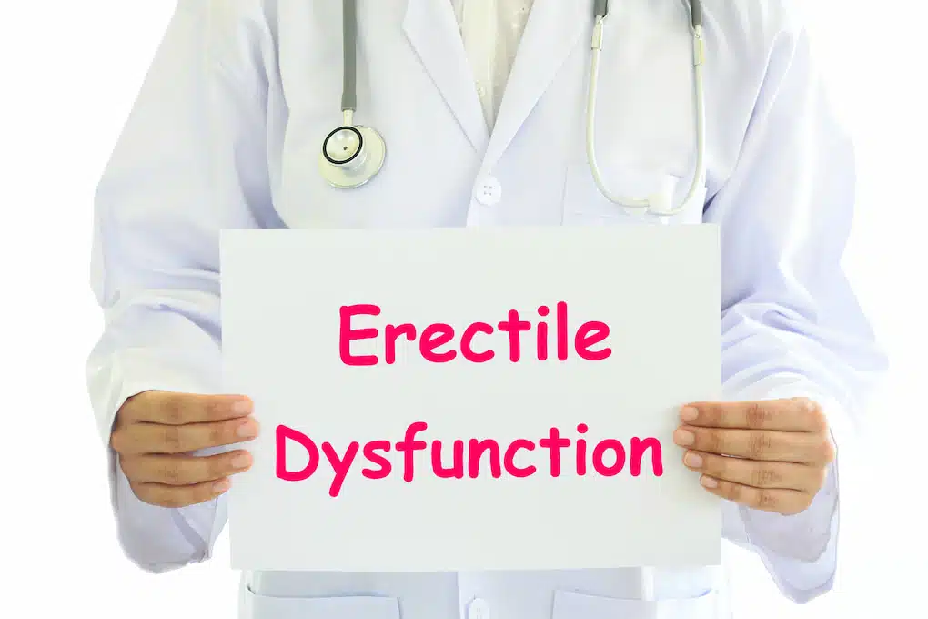 Doctor holding a white card board with Erectile Dysfunction concept on it.