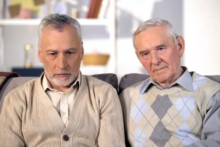 Image of two senior men sitting on the couch at home.
