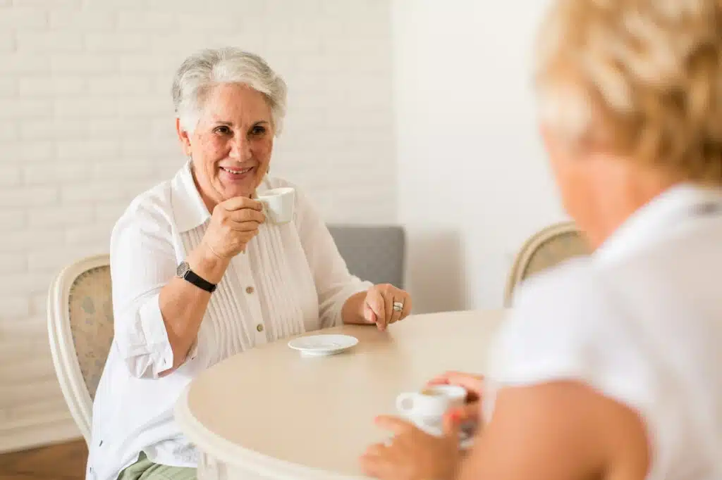 two old women drinking and talking at home.